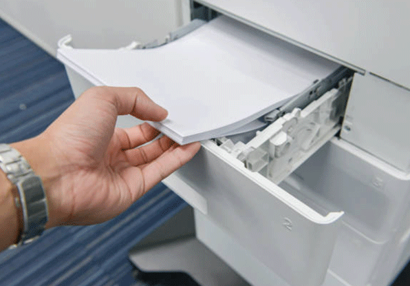 a man is reloading the paper at the printer tray